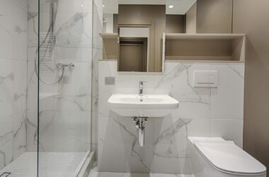 Minimalist bathroom with marble tiles, modern fixtures, and spacious design.